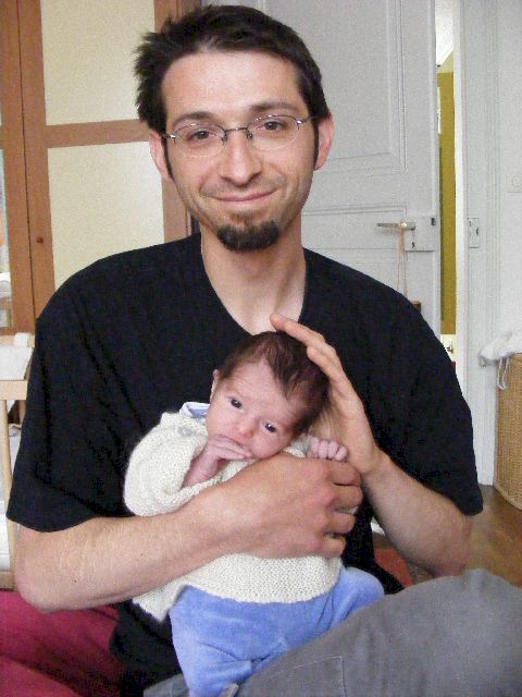 Un jeune papa avec son nouveau-né, quelques jours après le retour à la maison. L’enfant est encore tout fragile, le papa, tout ému, le tient avec précaution pour le rassurer. 