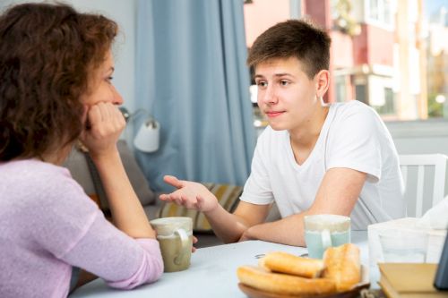 Suite à un problème en famille, un adolescent dialogue avec sa mère au petit déjeuner. Elle écoute avec patience et bienveillance l’explication de son fils, ils sont détendus. Il sera possible de trouver un compromis.